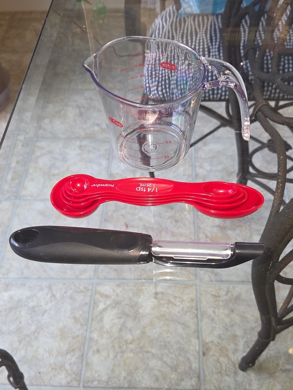Clear Glass Measuring Pitcher with Red Nesting Measuring Spoons and Black Peeler